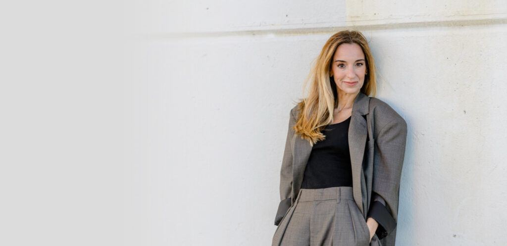Filipa Simões de Freitas, designer, docente e oradora, encostada a uma parede clara